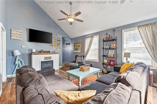 living room with high vaulted ceiling, ceiling fan, and light wood-type flooring