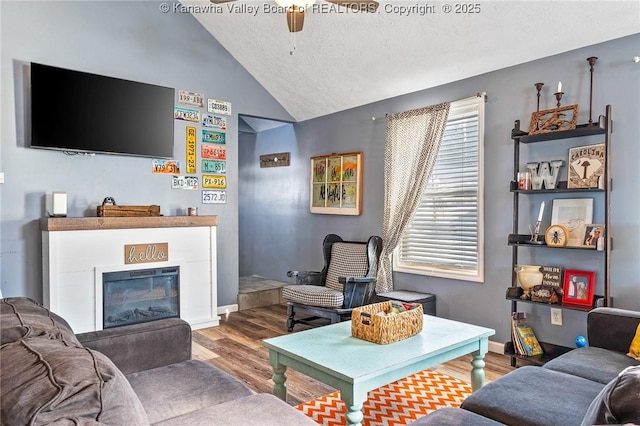 living room featuring vaulted ceiling, ceiling fan, a textured ceiling, and hardwood / wood-style flooring