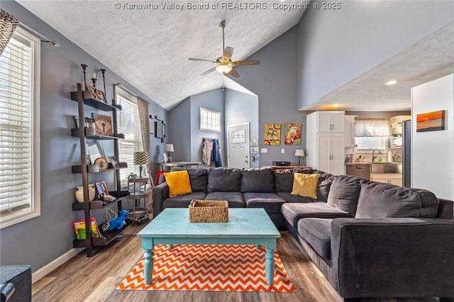 living room with lofted ceiling, ceiling fan, a textured ceiling, and wood-type flooring