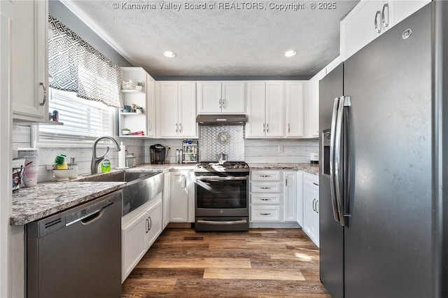 kitchen with light stone counters, stainless steel appliances, and white cabinetry