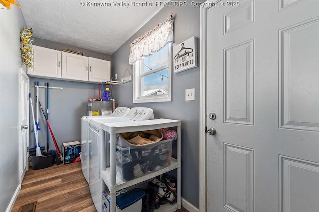 laundry room with washing machine and dryer, cabinets, dark hardwood / wood-style flooring, and a textured ceiling