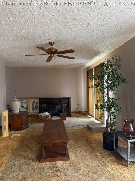 carpeted living room featuring a fireplace, a ceiling fan, and a textured ceiling