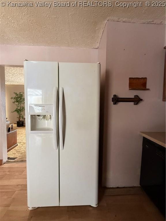 kitchen featuring a textured ceiling, white refrigerator with ice dispenser, and wood finished floors