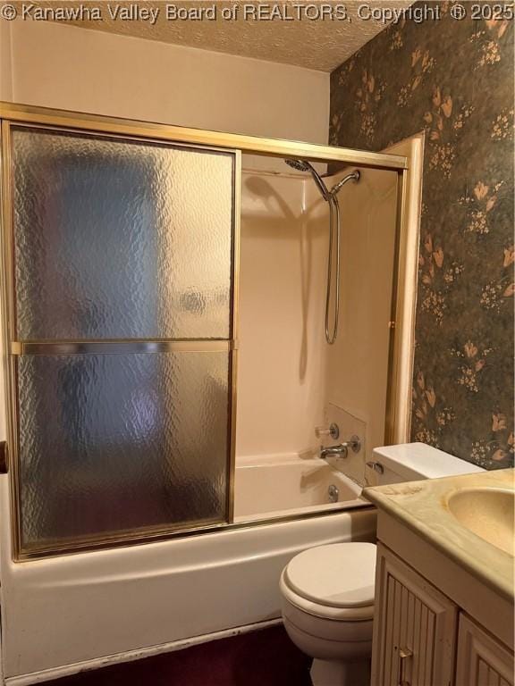 bathroom featuring a textured ceiling, toilet, vanity, combined bath / shower with glass door, and wallpapered walls