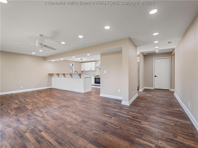 unfurnished living room featuring ceiling fan and dark wood-type flooring