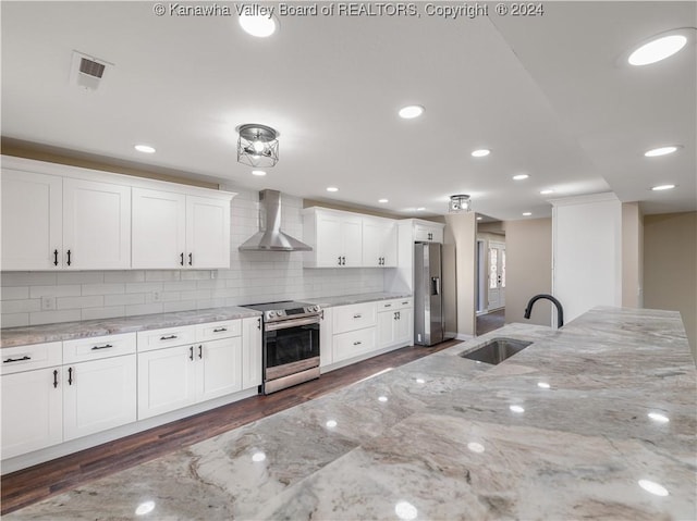 kitchen featuring light stone counters, white cabinets, appliances with stainless steel finishes, and wall chimney exhaust hood