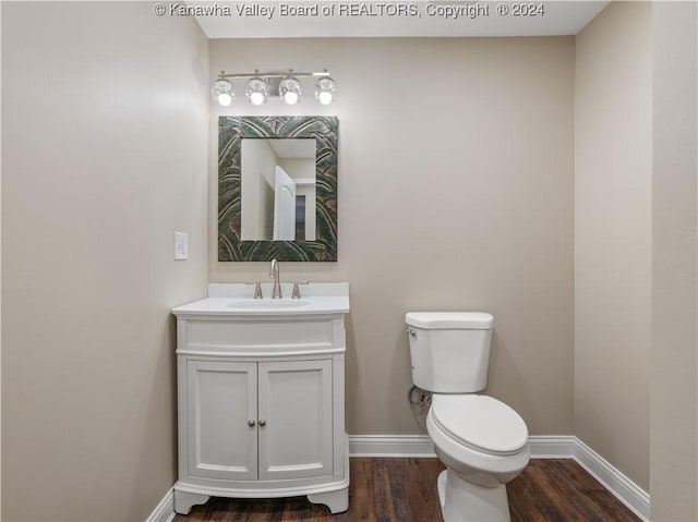 bathroom featuring toilet, vanity, and hardwood / wood-style floors