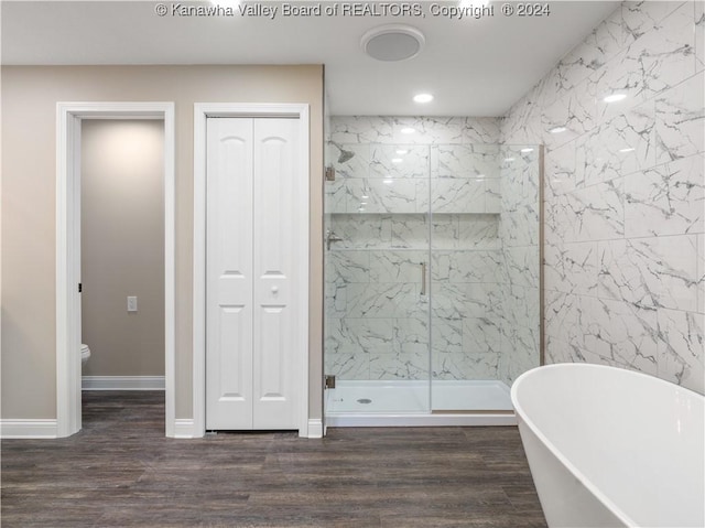 bathroom featuring hardwood / wood-style floors, toilet, and shower with separate bathtub