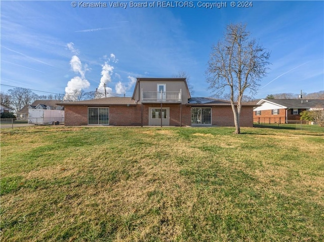 back of house with a balcony and a yard