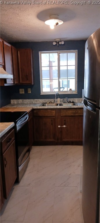 kitchen with a textured ceiling, stainless steel fridge, black range with electric stovetop, and sink