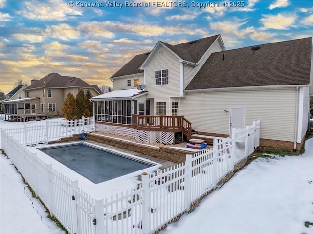 snow covered property featuring a wooden deck and a sunroom