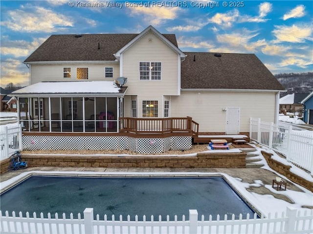 snow covered back of property featuring a sunroom and a pool side deck