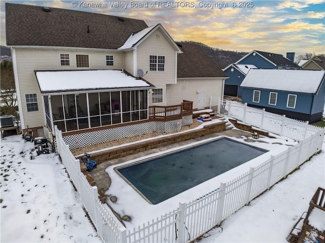 snow covered back of property featuring central AC unit and a sunroom