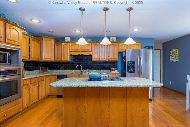 kitchen featuring decorative light fixtures, light hardwood / wood-style flooring, light stone counters, and a kitchen island