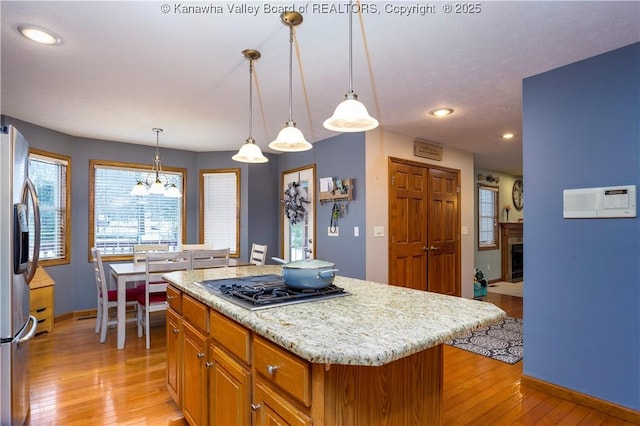 kitchen with light hardwood / wood-style flooring, pendant lighting, stainless steel appliances, and a center island