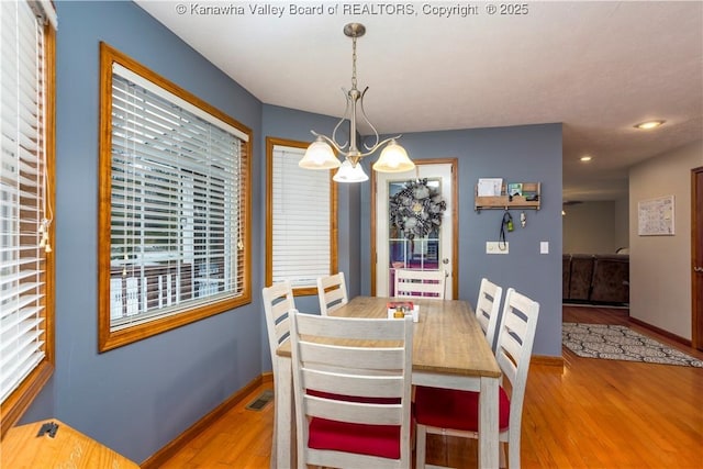 dining space featuring plenty of natural light, hardwood / wood-style floors, and a notable chandelier