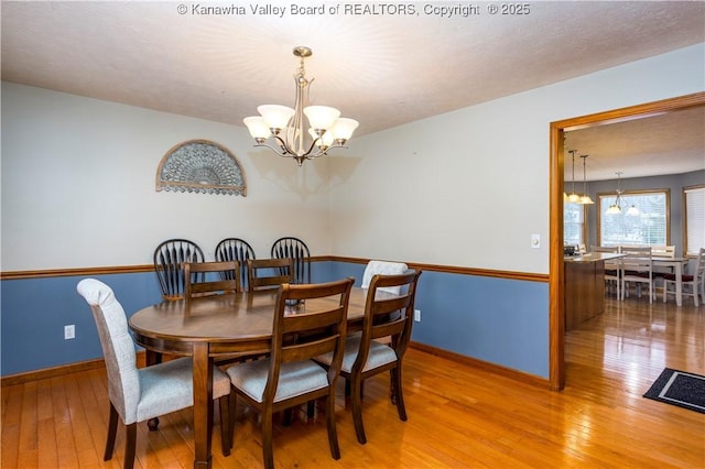 dining area featuring wood-type flooring and a notable chandelier