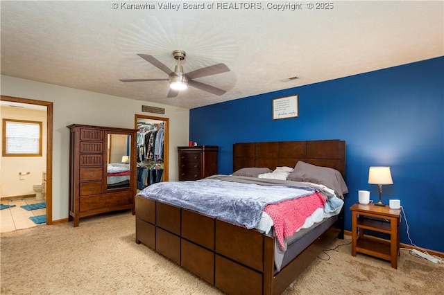 bedroom featuring a spacious closet, light carpet, ensuite bathroom, ceiling fan, and a closet