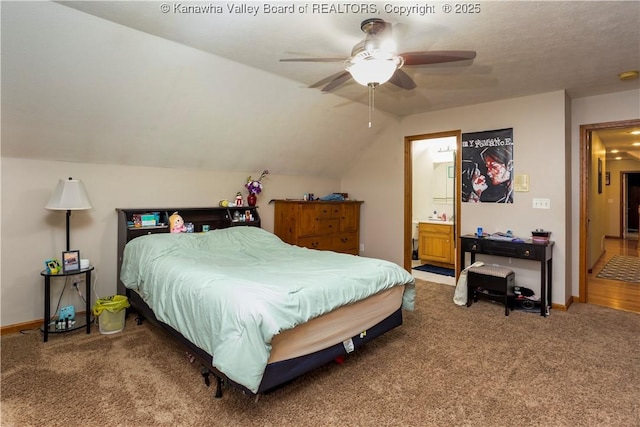 bedroom featuring ensuite bathroom, ceiling fan, carpet flooring, and vaulted ceiling