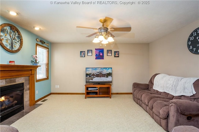 carpeted living room featuring ceiling fan and a tile fireplace