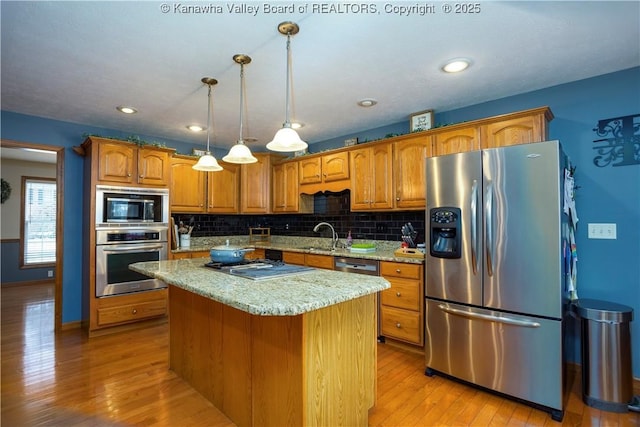 kitchen with stainless steel appliances, light hardwood / wood-style floors, a kitchen island, and decorative light fixtures