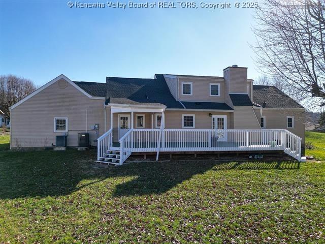 rear view of house with central AC unit, a lawn, and a wooden deck