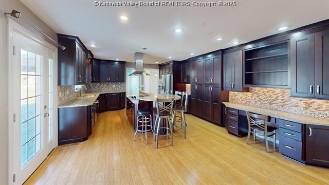 kitchen featuring light wood finished floors, a breakfast bar area, light countertops, built in study area, and stainless steel fridge