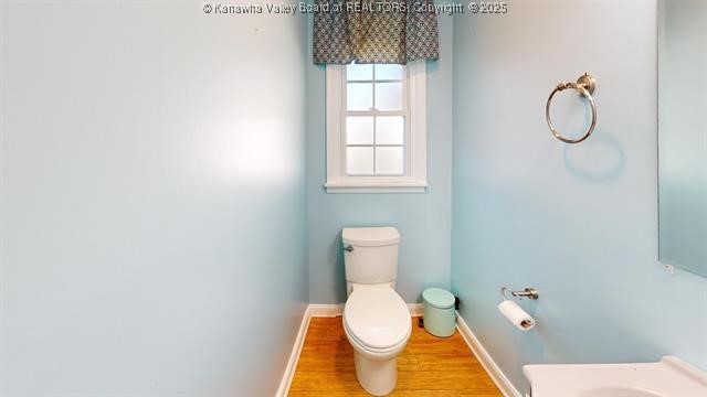 half bath featuring toilet, baseboards, and wood finished floors