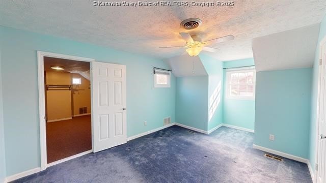 additional living space featuring visible vents, a textured ceiling, and carpet flooring