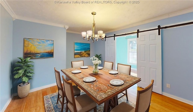 dining room with baseboards, a barn door, light wood-type flooring, and crown molding