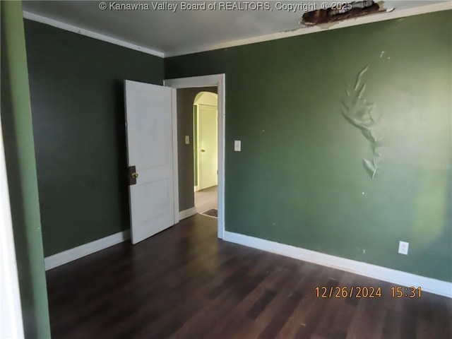 spare room featuring dark hardwood / wood-style flooring and crown molding