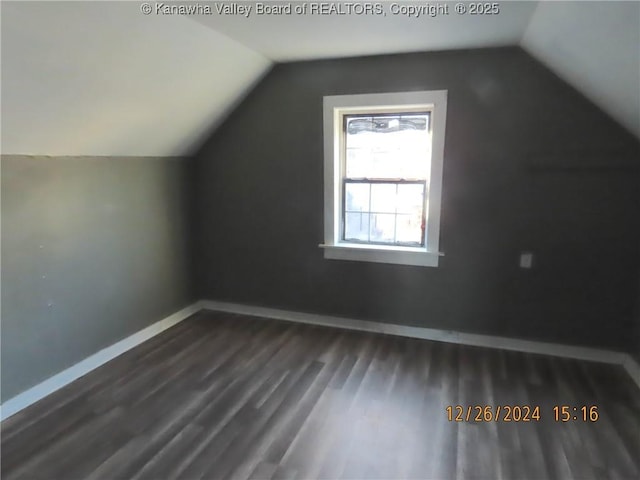 additional living space with vaulted ceiling and dark hardwood / wood-style flooring