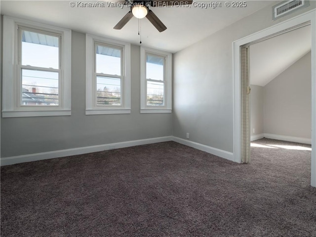 empty room with ceiling fan, vaulted ceiling, and dark colored carpet