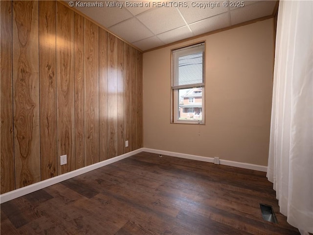 empty room featuring a paneled ceiling and dark hardwood / wood-style flooring