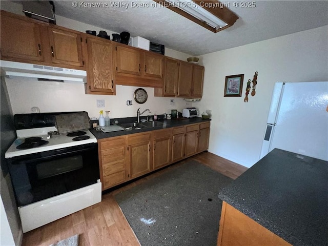 kitchen with a textured ceiling, dark hardwood / wood-style flooring, white refrigerator, electric stove, and sink