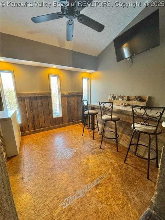 dining room featuring a textured ceiling and wood walls