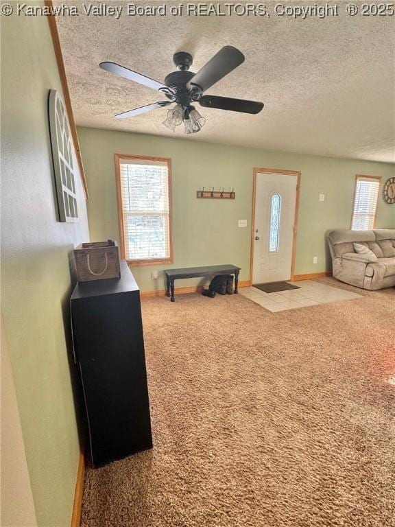 carpeted foyer entrance with ceiling fan, a healthy amount of sunlight, and a textured ceiling