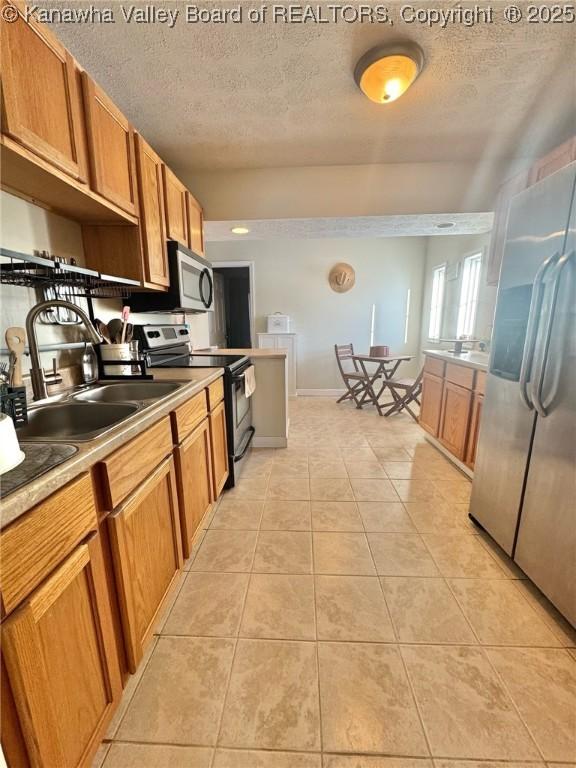 kitchen featuring light tile patterned floors, sink, stainless steel appliances, and a textured ceiling