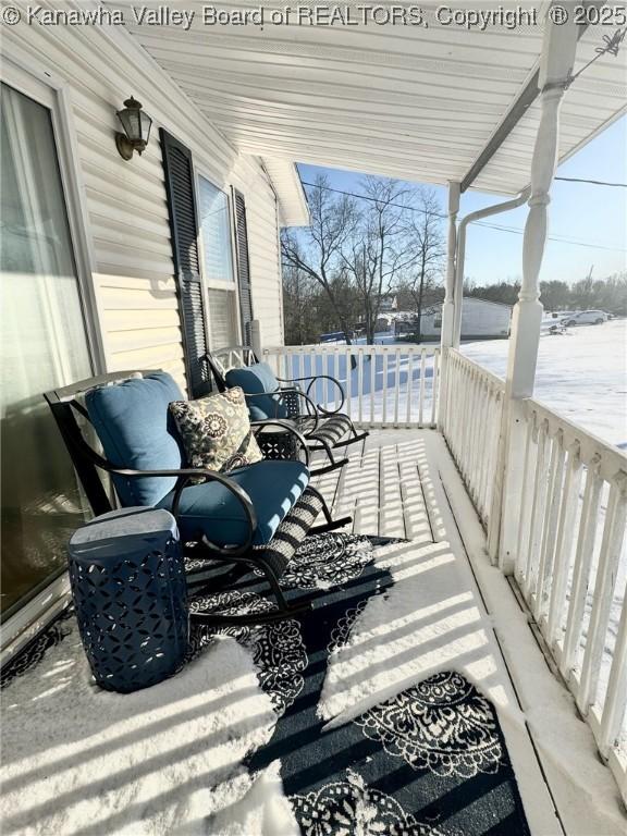 snow covered deck featuring covered porch