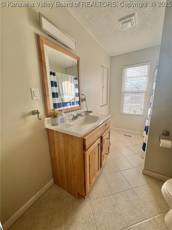 bathroom featuring toilet, a textured ceiling, tile patterned floors, and vanity