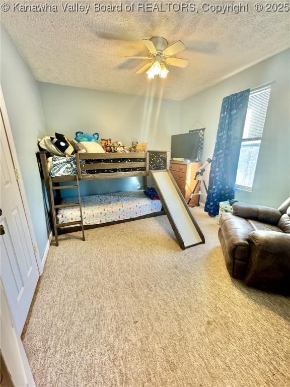 bedroom featuring a textured ceiling, ceiling fan, and carpet