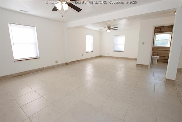 tiled spare room featuring ceiling fan and a healthy amount of sunlight