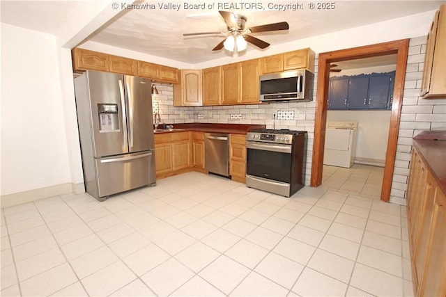 kitchen featuring sink, ceiling fan, stainless steel appliances, washer / clothes dryer, and decorative backsplash