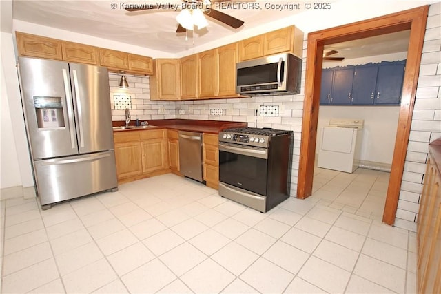 kitchen with appliances with stainless steel finishes, tasteful backsplash, washer / dryer, sink, and ceiling fan