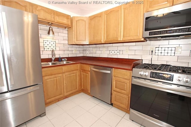 kitchen featuring appliances with stainless steel finishes, sink, light tile patterned floors, and backsplash