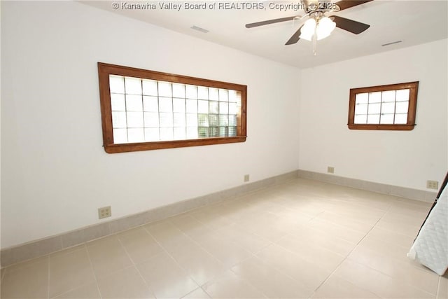 empty room featuring plenty of natural light, light tile patterned floors, and ceiling fan