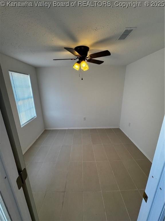 unfurnished room with ceiling fan and a textured ceiling