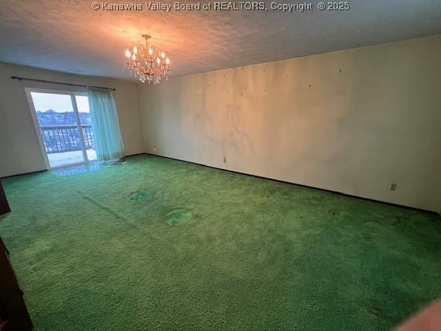 unfurnished room with carpet, a textured ceiling, and a chandelier