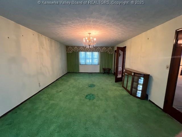 spare room with carpet, a notable chandelier, and a textured ceiling