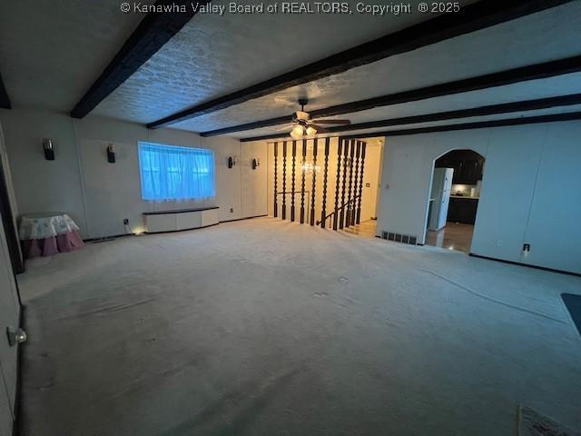 unfurnished living room featuring concrete flooring, ceiling fan, and beam ceiling